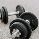 Massive metal dumbbells prepared for difficult healthy training on asphalt road in summer