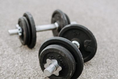 Massive metal dumbbells prepared for difficult healthy training on asphalt road in summer