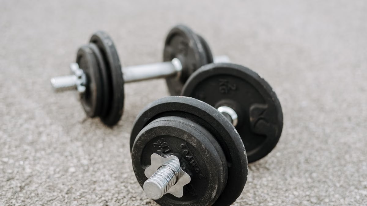 Massive metal dumbbells prepared for difficult healthy training on asphalt road in summer